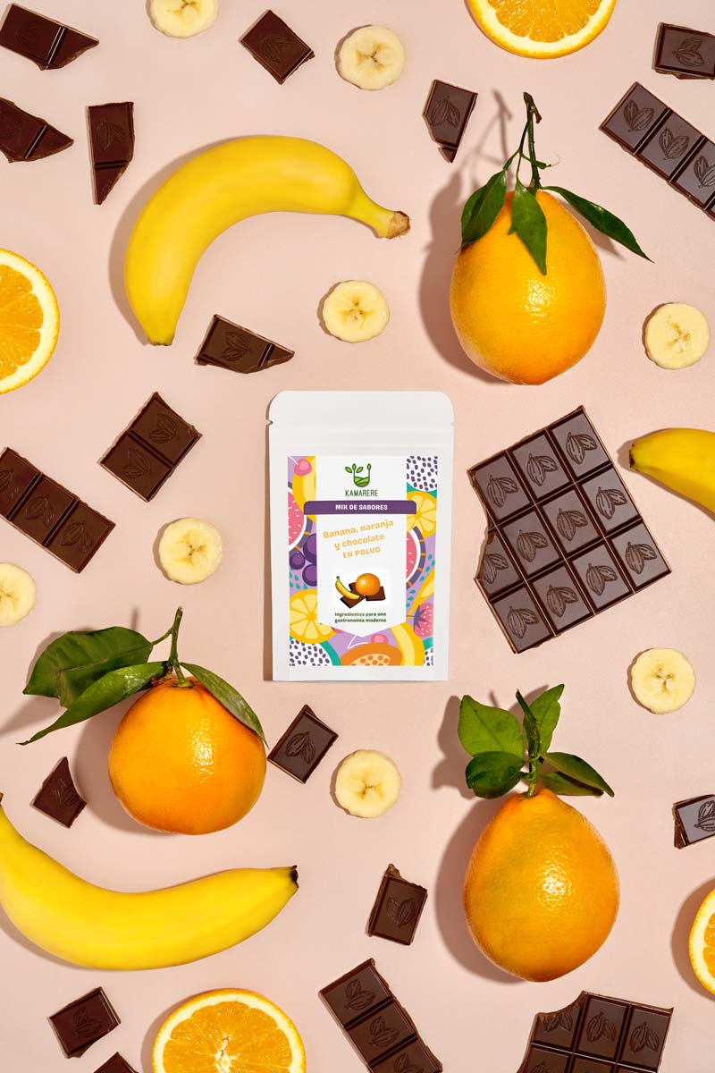 Captivating flat lay photograph featuring a white packaging filled with a finely powdered blend of fresh seasonal ingredients. Surrounding the packaging, you'll find jfresh oranges and dark chocolate pieces. This exquisite studio product photography showcases the essence of the Kamarere food brand.