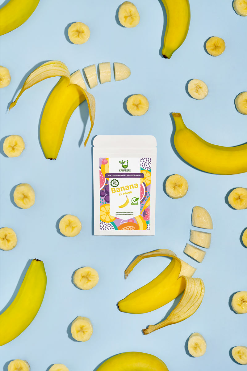 Captivating flat lay photograph featuring a white packaging filled with a finely powdered blend of fresh seasonal ingredients. Surrounding the packaging, you'll find fresh bananas. This exquisite studio product photography showcases the essence of the Kamarere food brand.