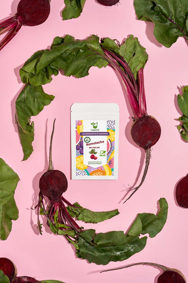 Captivating flat lay photograph featuring a white packaging filled with a finely powdered blend of fresh seasonal ingredients. Surrounding the packaging, you'll find fresh beetroots. This exquisite studio product photography showcases the essence of the Kamarere food brand.