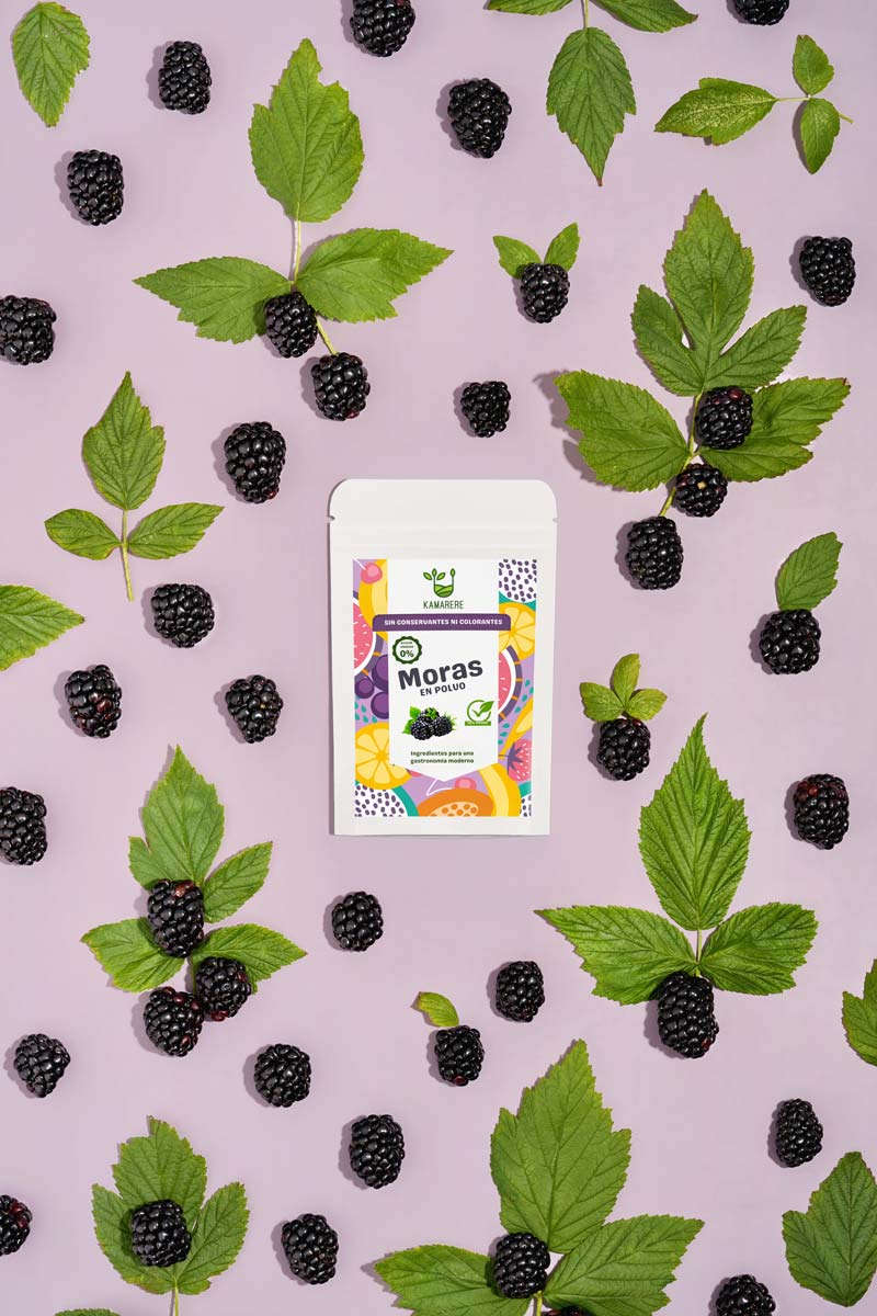 Captivating flat lay photograph featuring a white packaging filled with a finely powdered blend of fresh seasonal ingredients. Surrounding the packaging, you'll find juicy blackberries. This exquisite studio product photography showcases the essence of the Kamarere food brand.
