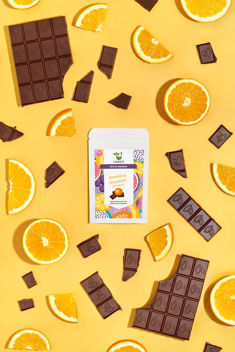 Captivating flat lay photograph featuring a white packaging filled with a finely powdered blend of fresh seasonal ingredients. Surrounding the packaging, you'll find jfresh oranges and dark chocolate pieces. This exquisite studio product photography showcases the essence of the Kamarere food brand.