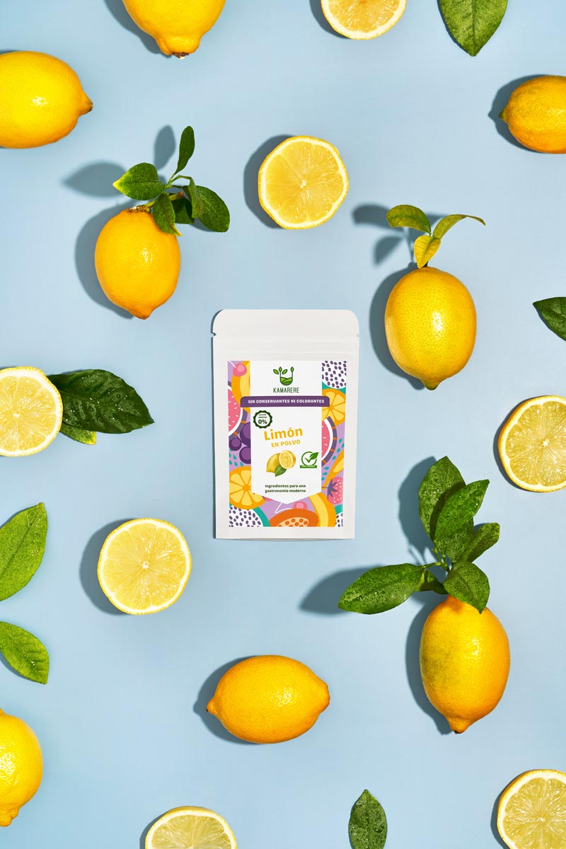 Captivating flat lay photograph featuring a white packaging filled with a finely powdered blend of fresh seasonal ingredients. Surrounding the packaging, you'll find juicy lemons. This exquisite studio product photography showcases the essence of the Kamarere food brand.