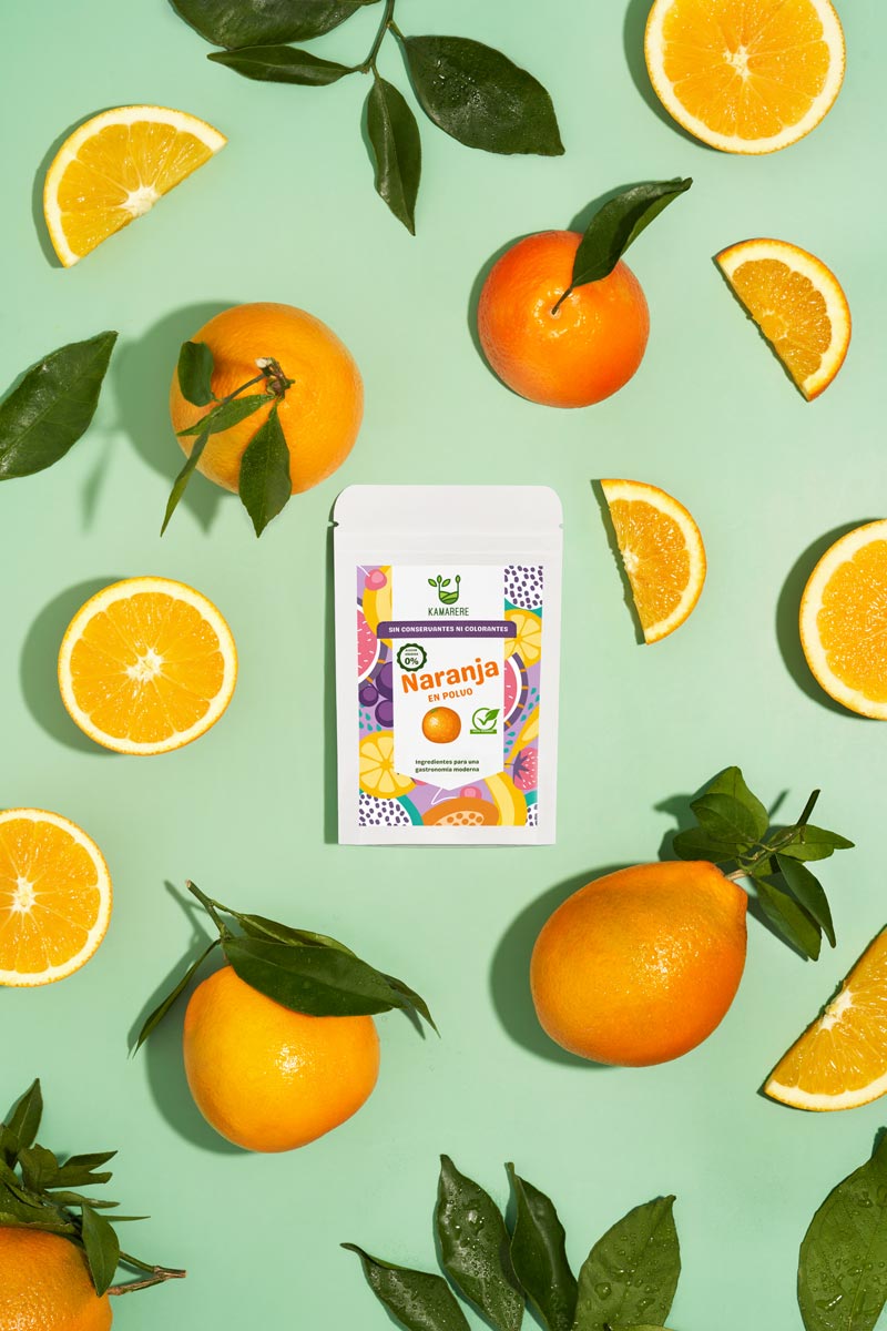 Captivating flat lay photograph featuring a white packaging filled with a finely powdered blend of fresh seasonal ingredients. Surrounding the packaging, you'll find juicy oranges directly from the tree. This exquisite studio product photography showcases the essence of the Kamarere food brand.