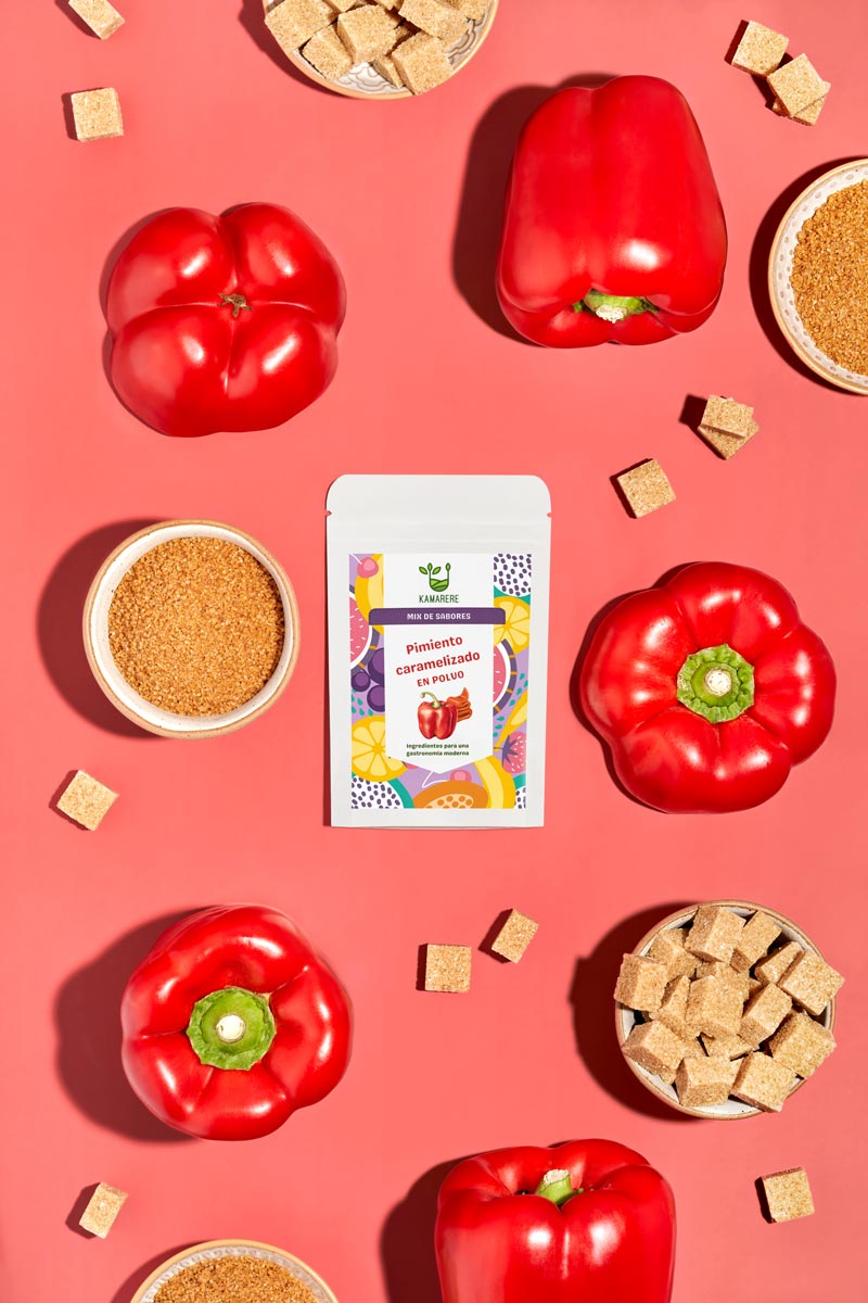 Captivating flat lay photograph featuring a white packaging filled with a finely powdered blend of fresh seasonal ingredients. Surrounding the packaging, you'll find fresh red pepper and sugar, the ingedients used in the powder production process. This exquisite studio product photography showcases the essence of the Kamarere food brand.
